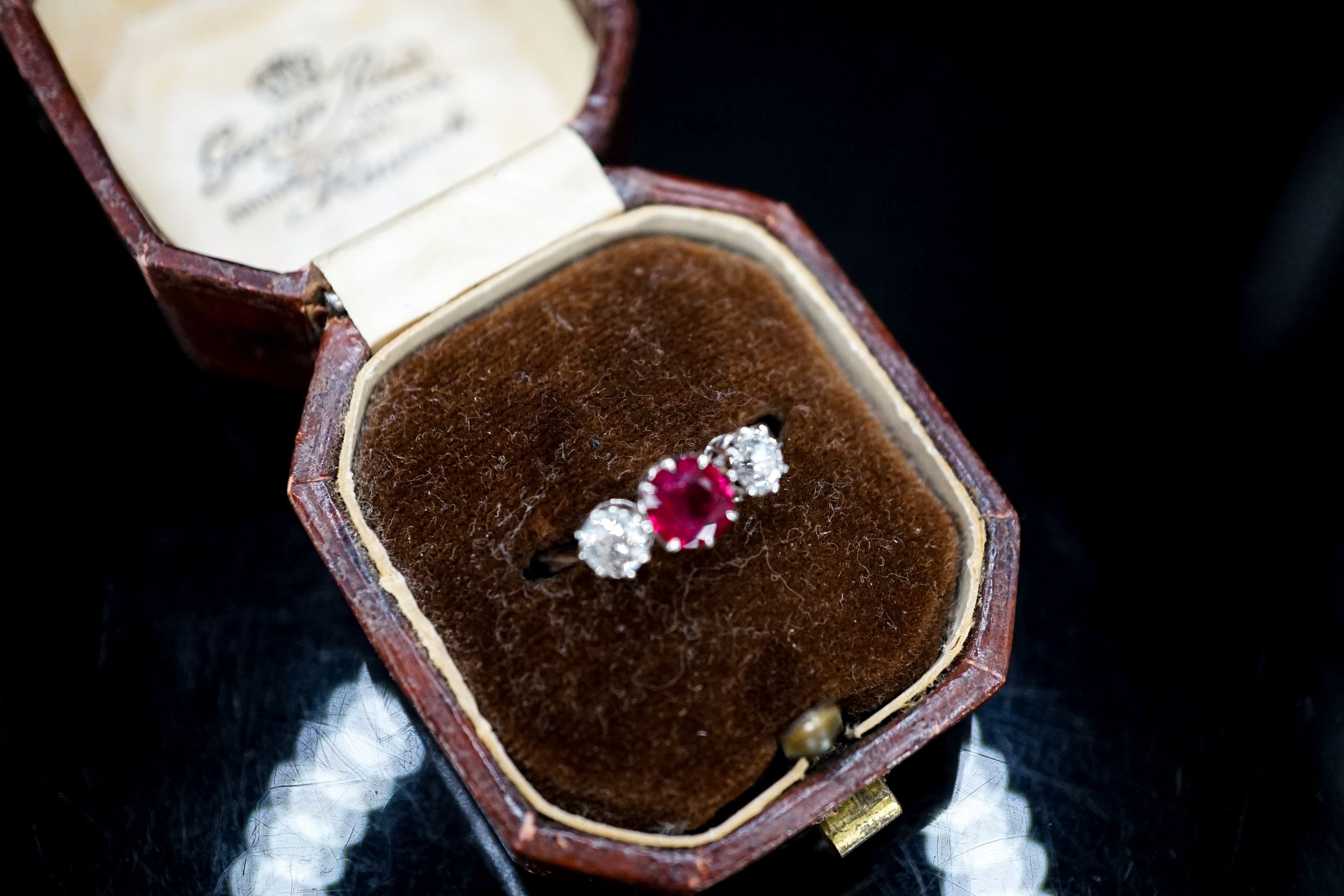 A white metal single stone ruby and two stone diamond ring, size L/M, gross weight 3 grams.